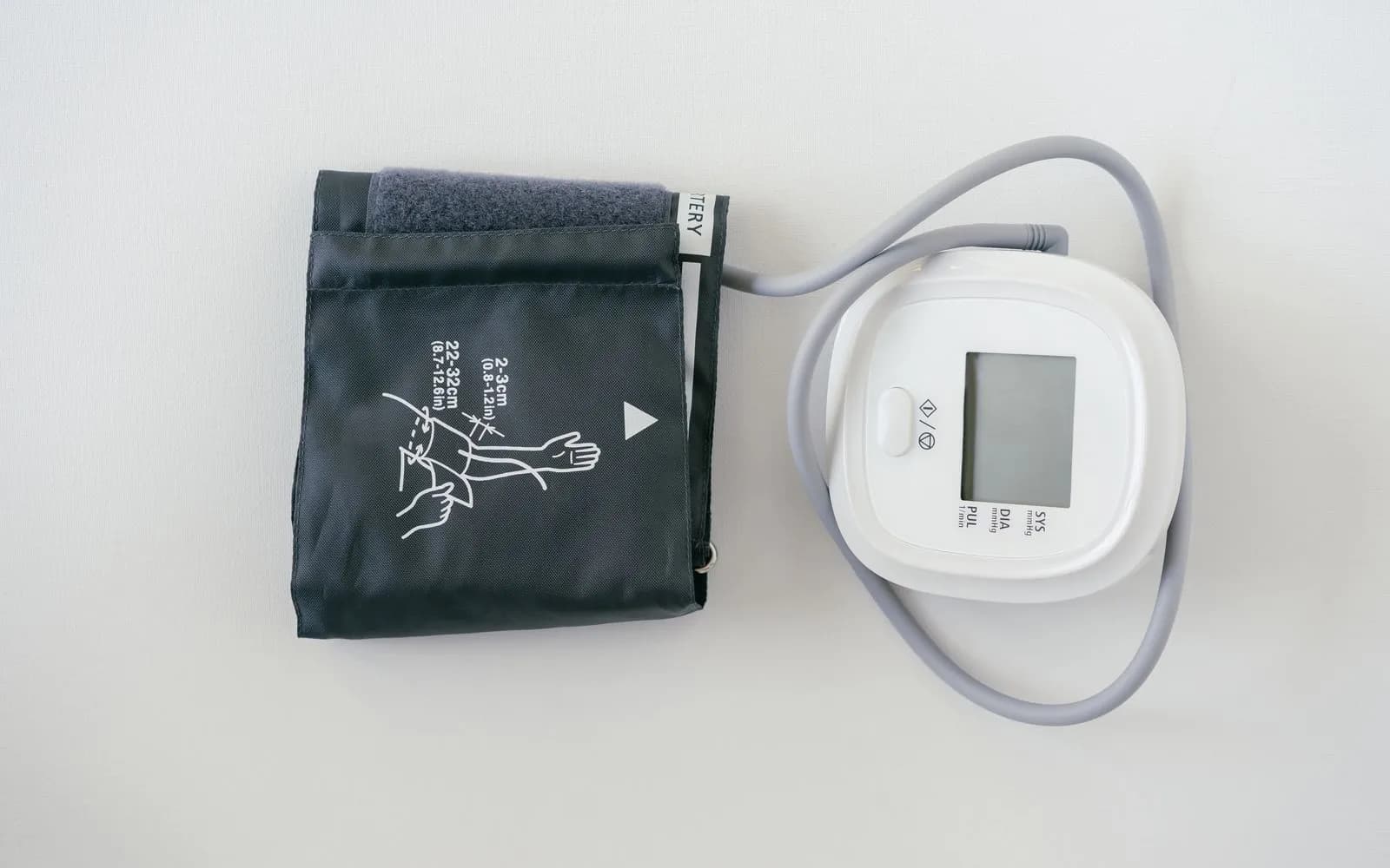 A home blood pressure monitor with its folded arm cuff on a plain white surface