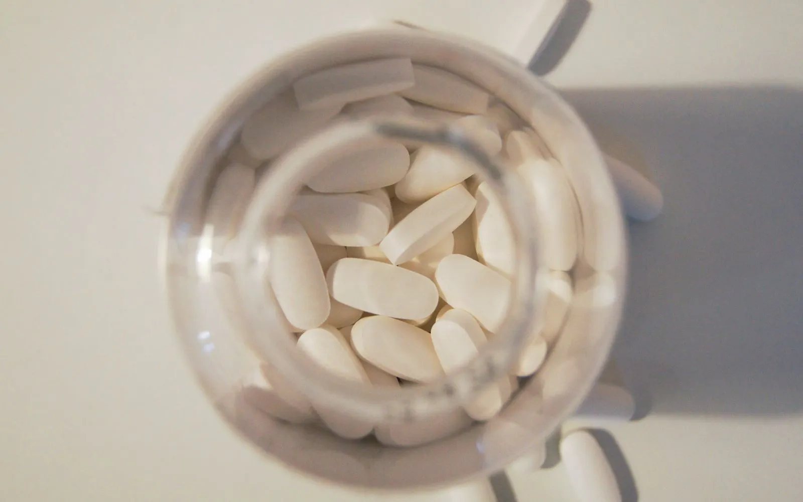 Large white oval tablets seen from above inside a clear glass jar