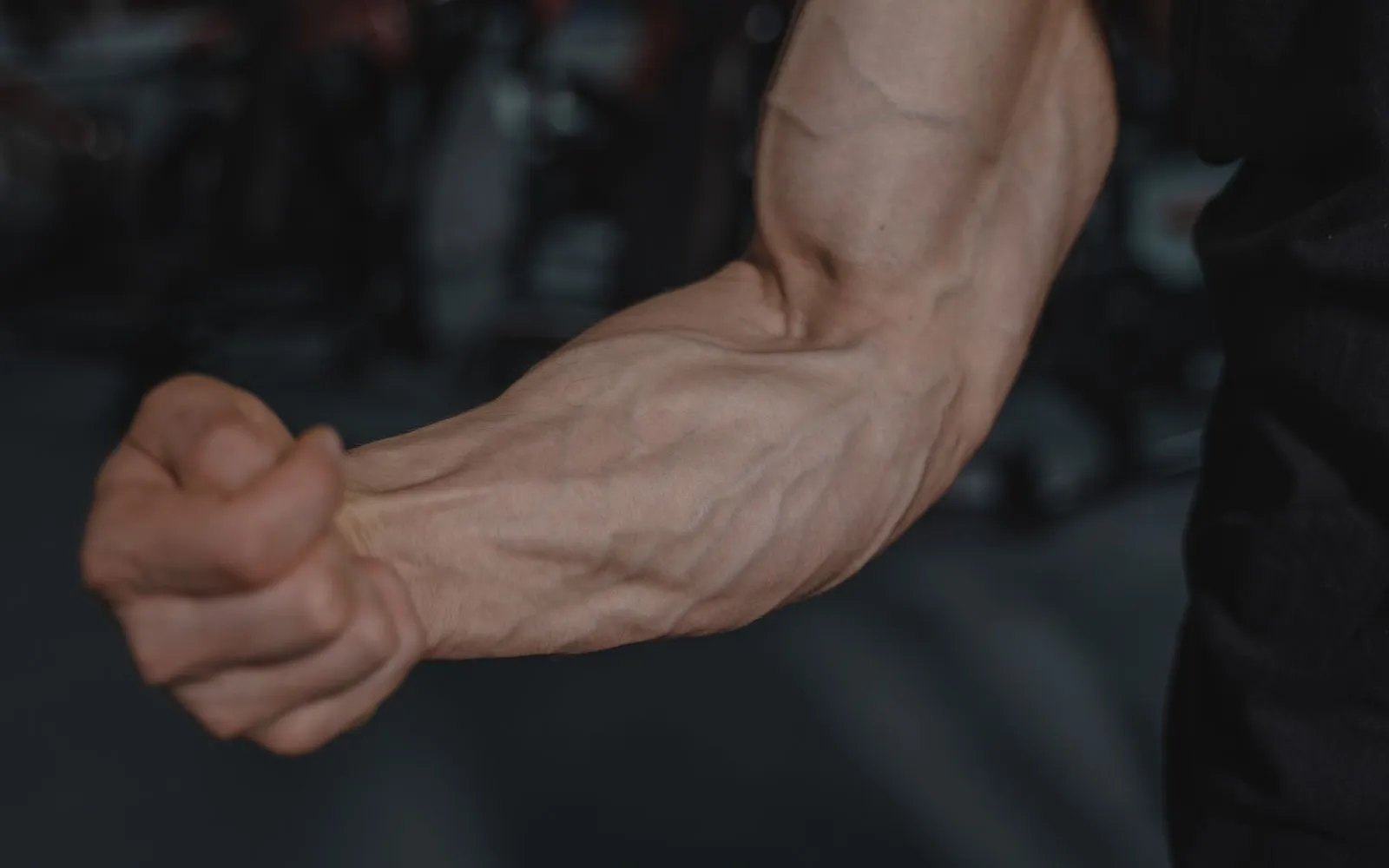 A forearm and clenched fist with the muscles showing, in a gym