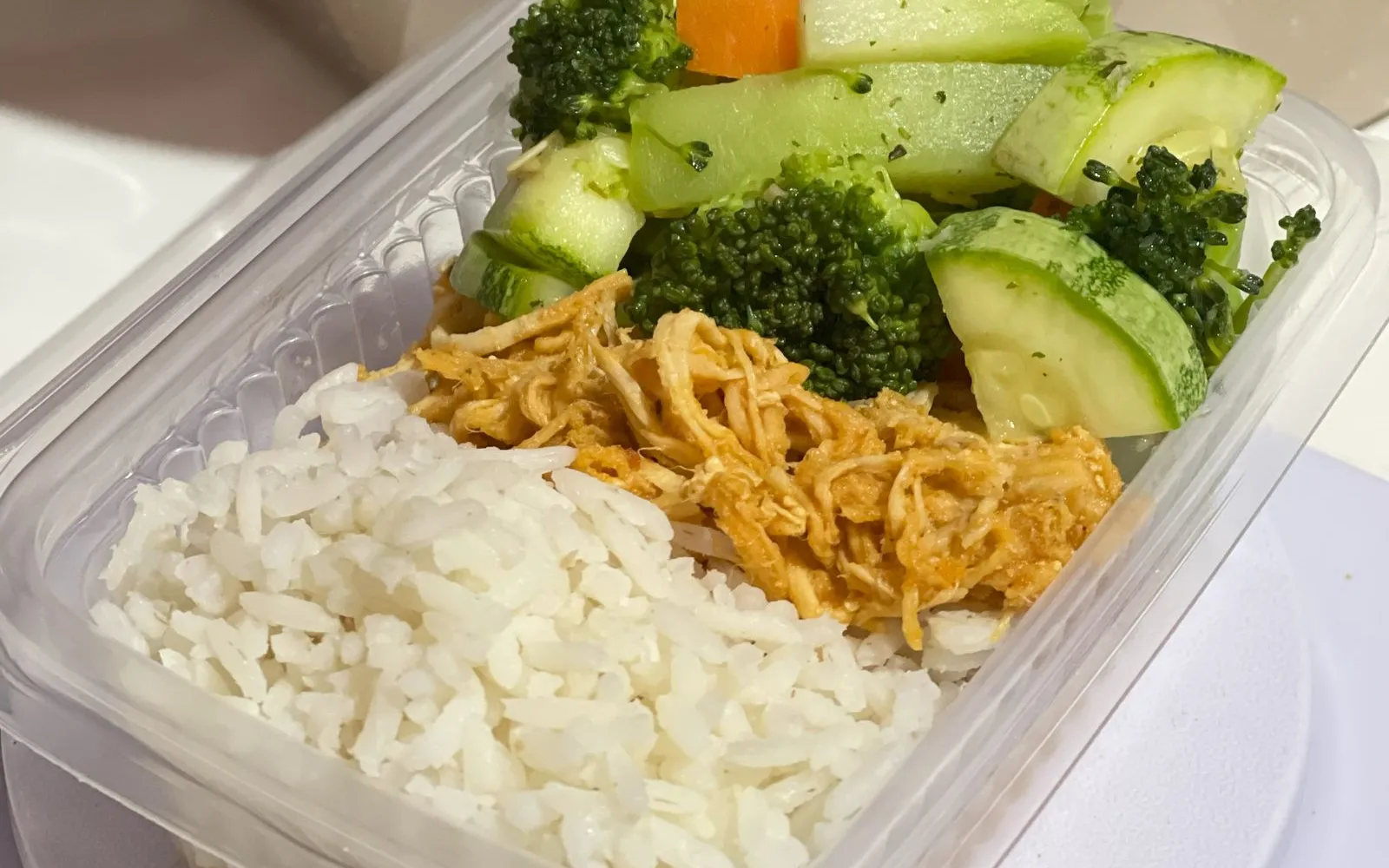 A meal prep box with white rice, shredded chicken, broccoli, courgette and carrot