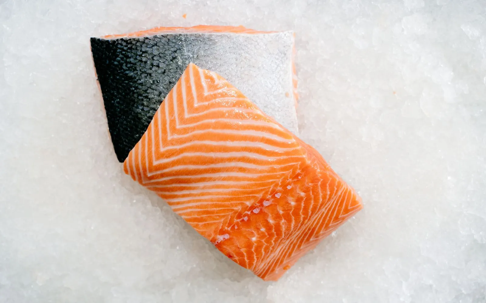 Two raw salmon fillets on crushed ice, ready to cook